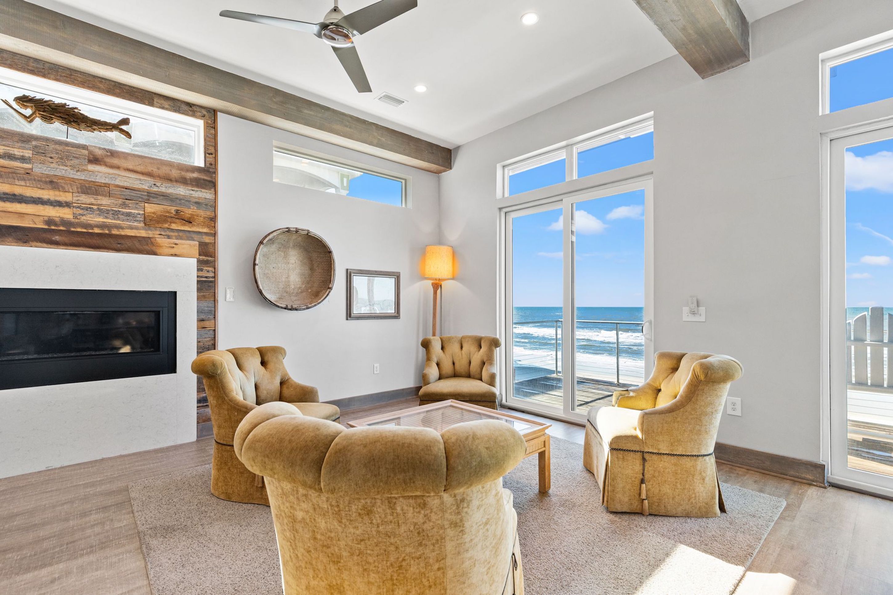 A spacious living room with a fireplace, large windows, and a view of the ocean.