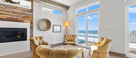 A spacious living room with a fireplace, large windows, and a view of the ocean.