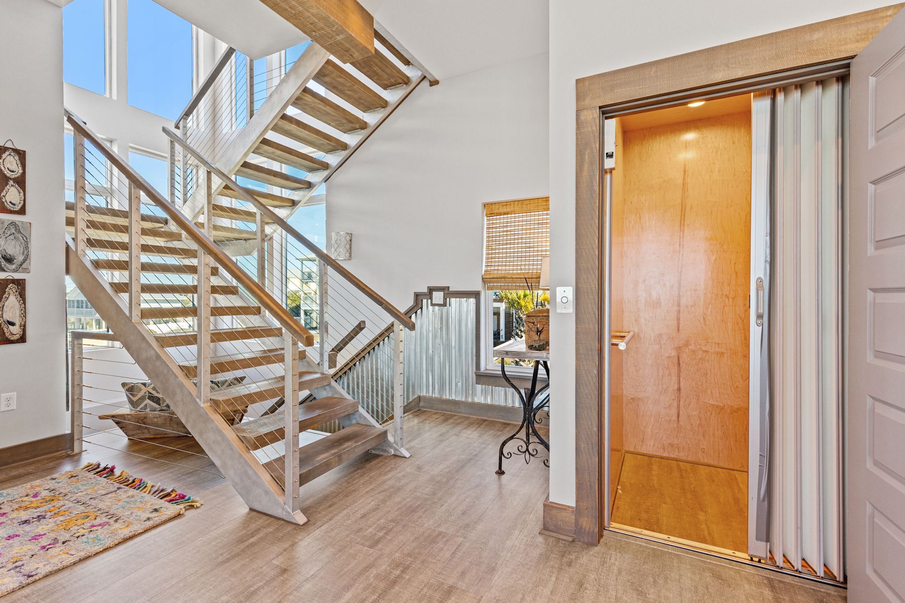 A modern interior with a wooden staircase, a wooden door, and a view of the outdoors.