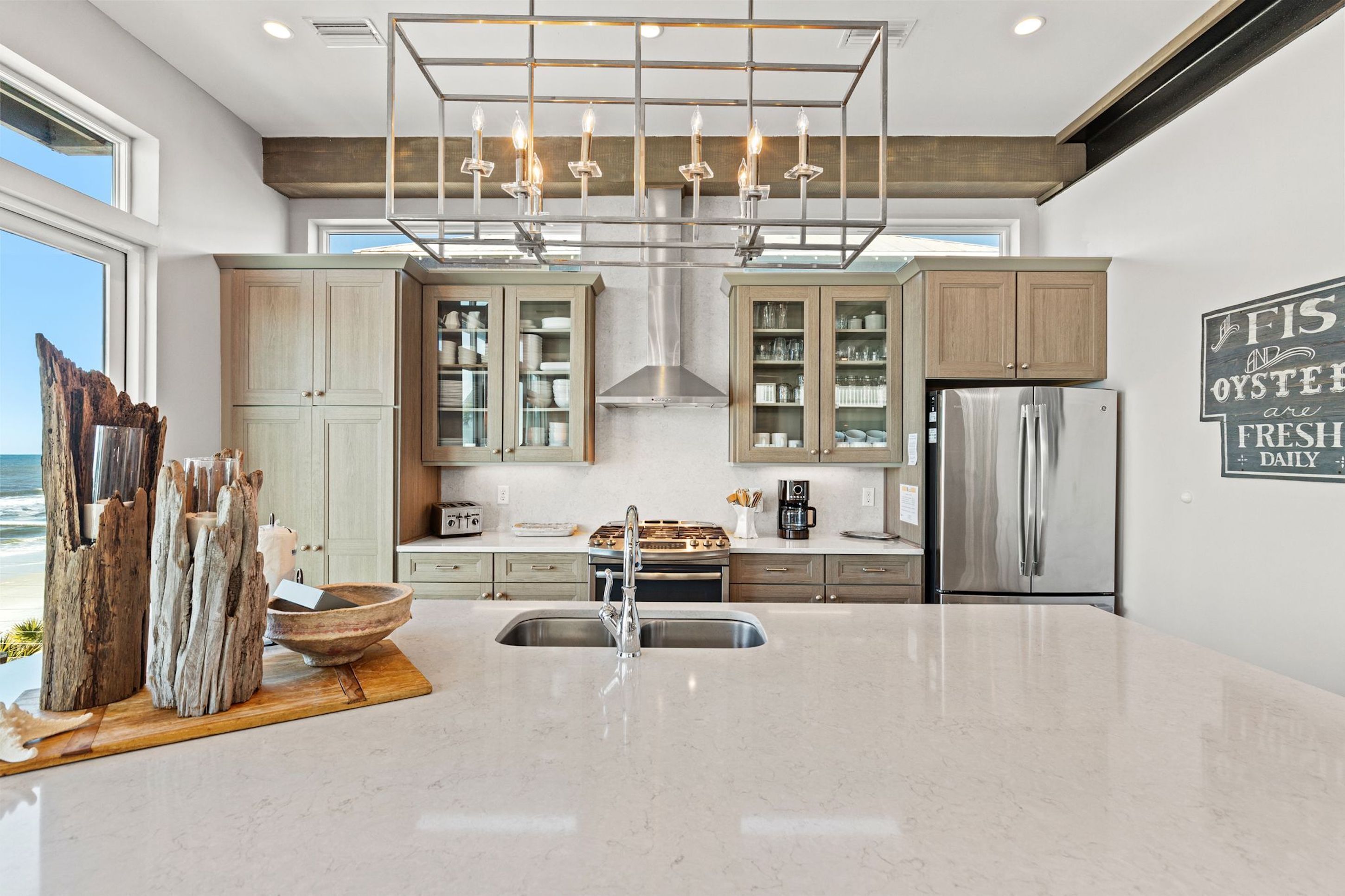 A modern kitchen with a large island, stainless steel appliances, and a view of the ocean.