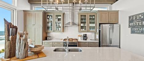 A modern kitchen with a large island, stainless steel appliances, and a view of the ocean.