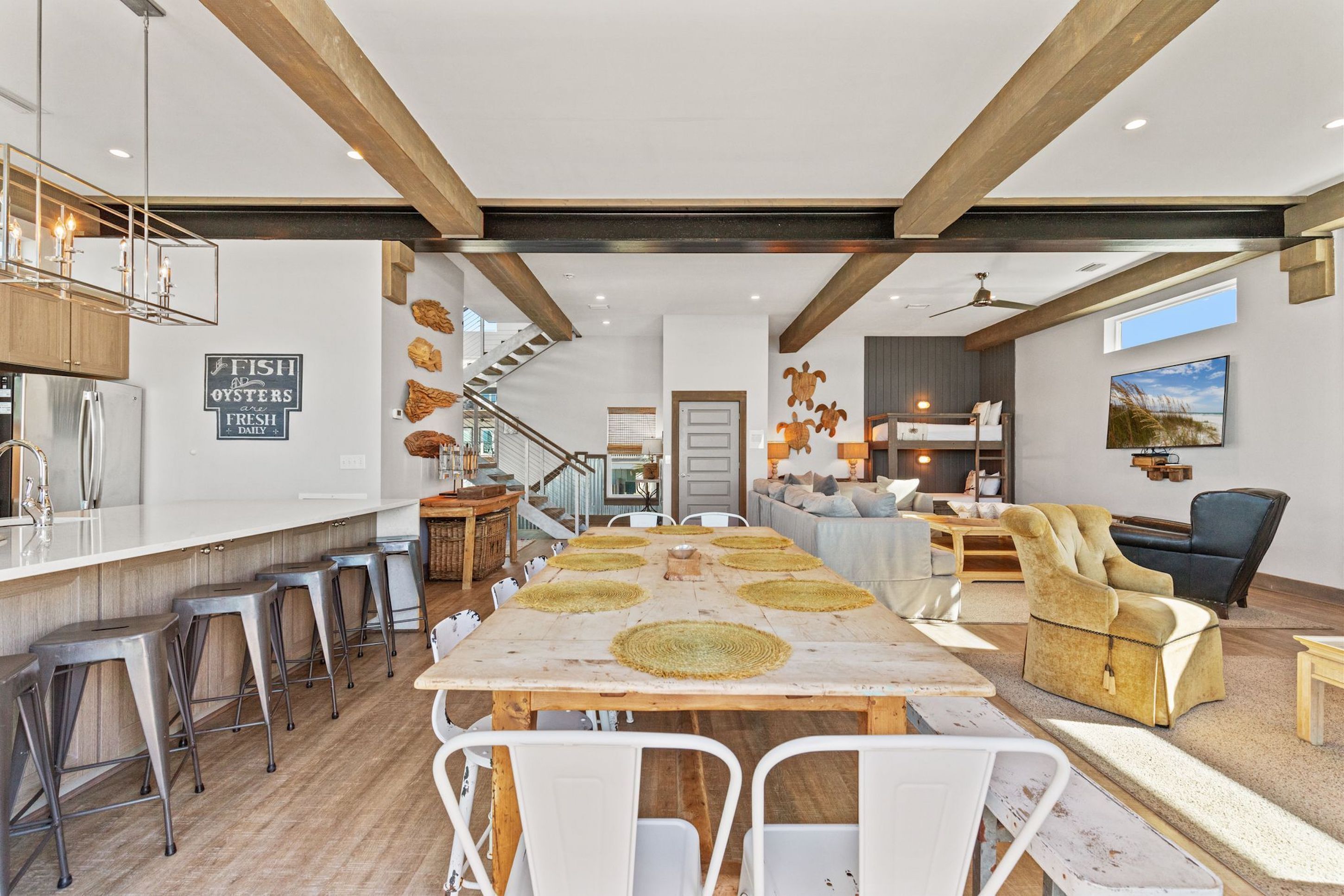Un vaste espace de vie comprenant une grande table en bois, des chaises blanches et un canapé.