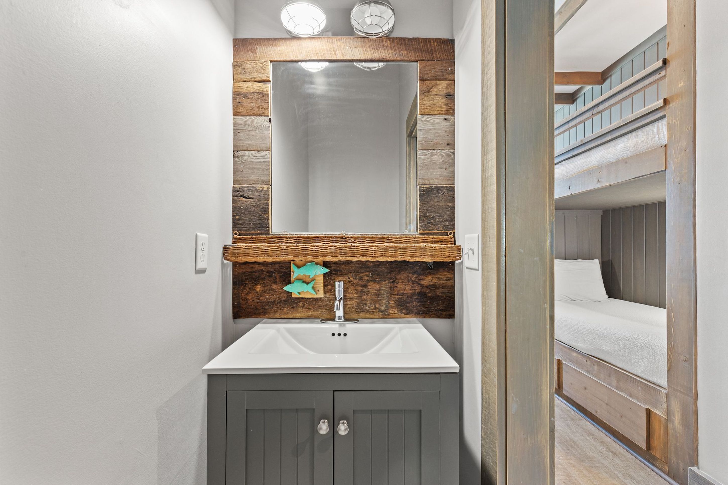 A bathroom with a wooden wall, a white sink, and a mirror.