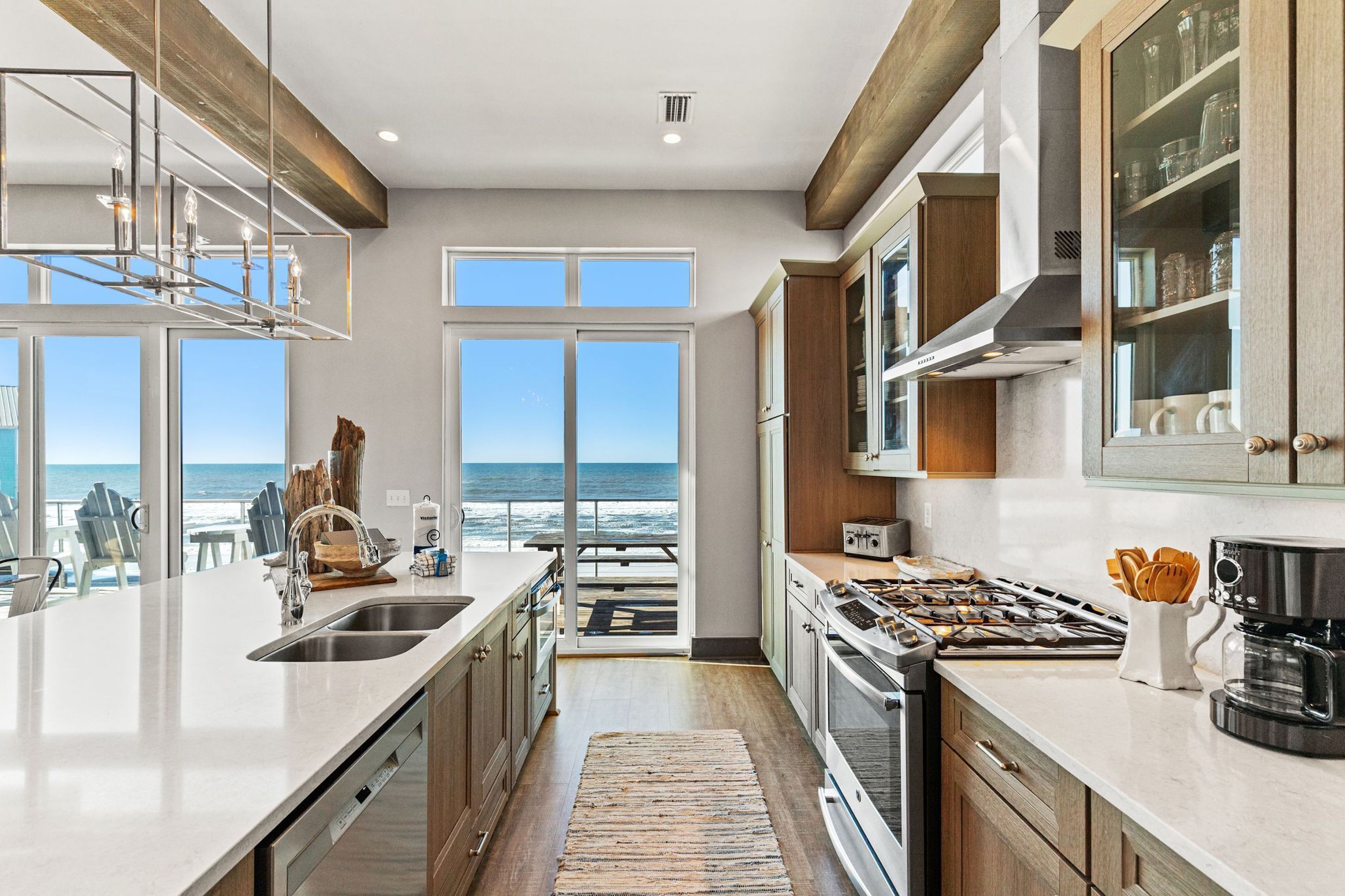 A modern kitchen with a large island, stainless steel appliances, and a view of the ocean through large windows.