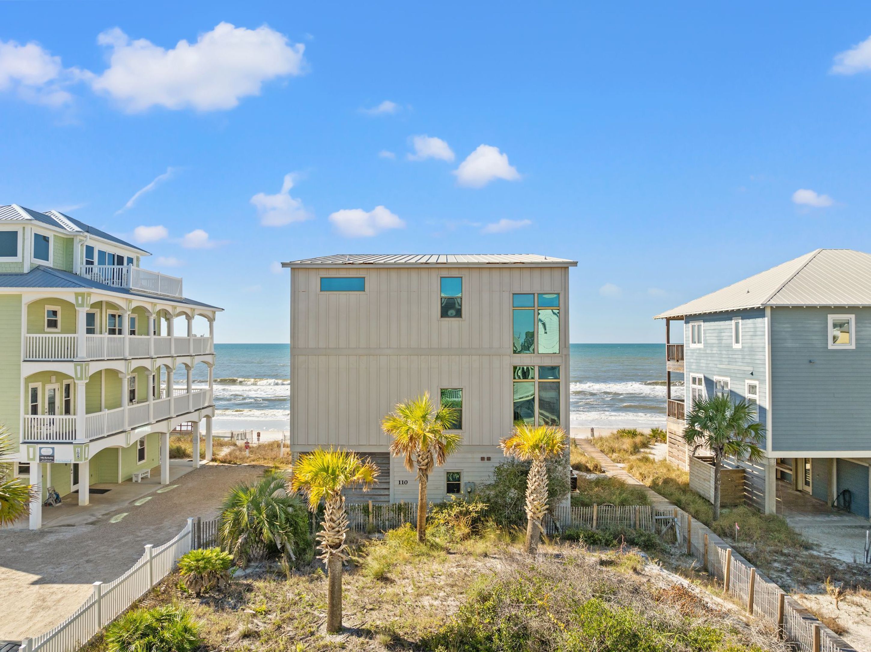 A beachfront property with a central building, a multi-story structure with balconies, and a beach view.
