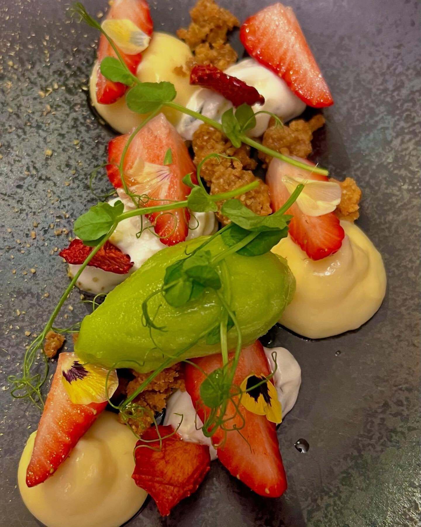Une assiette de dessert garnie de fraises, de crème et d’une verdure.