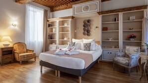 Un dormitorio espacioso con una cama grande, suelo de madera, estanterías integradas y un clásico candelabro.
