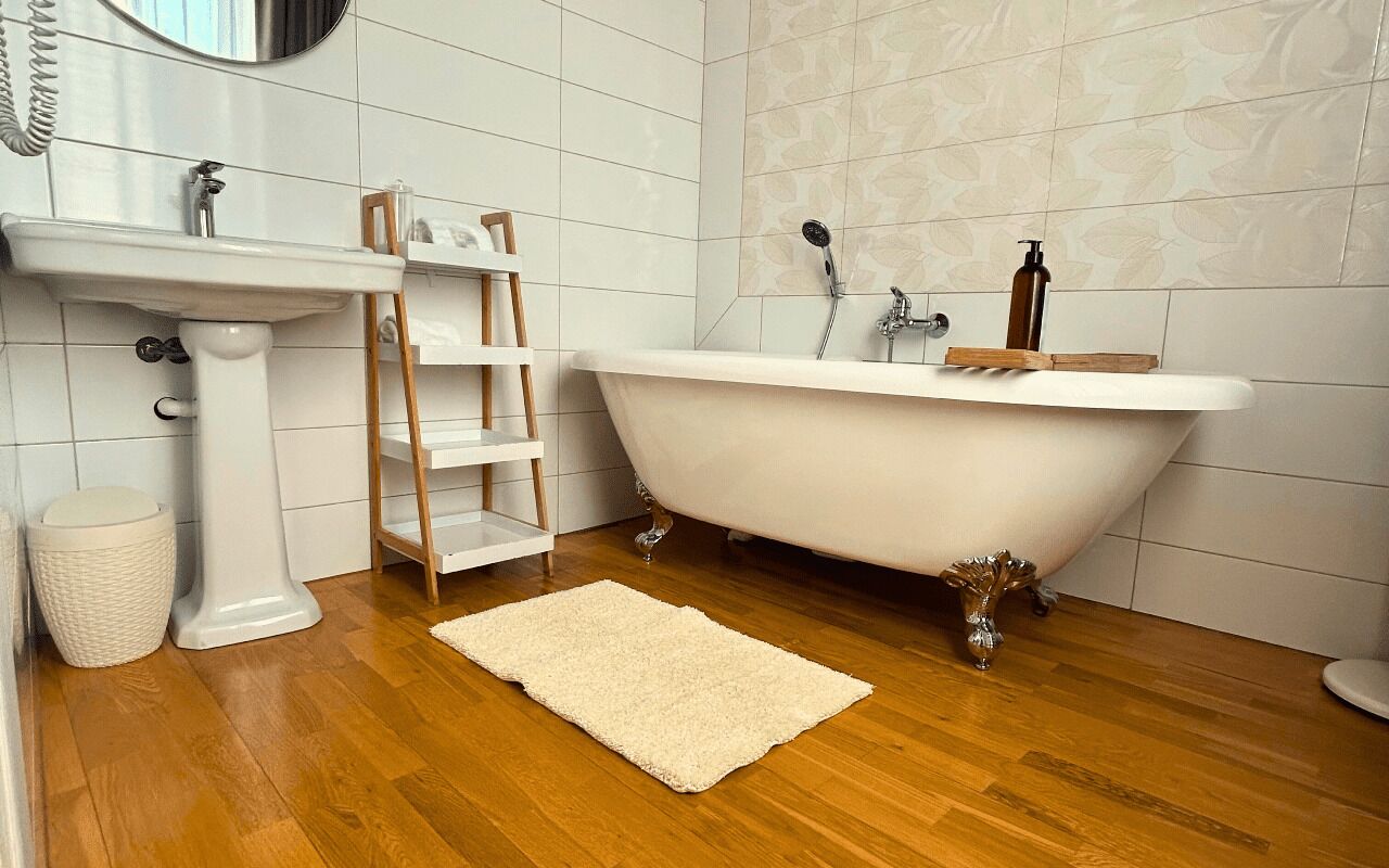 Une salle de bain avec une baignoire îlot blanche, un lavabo sur colonne et une étagère en bois de style échelle.