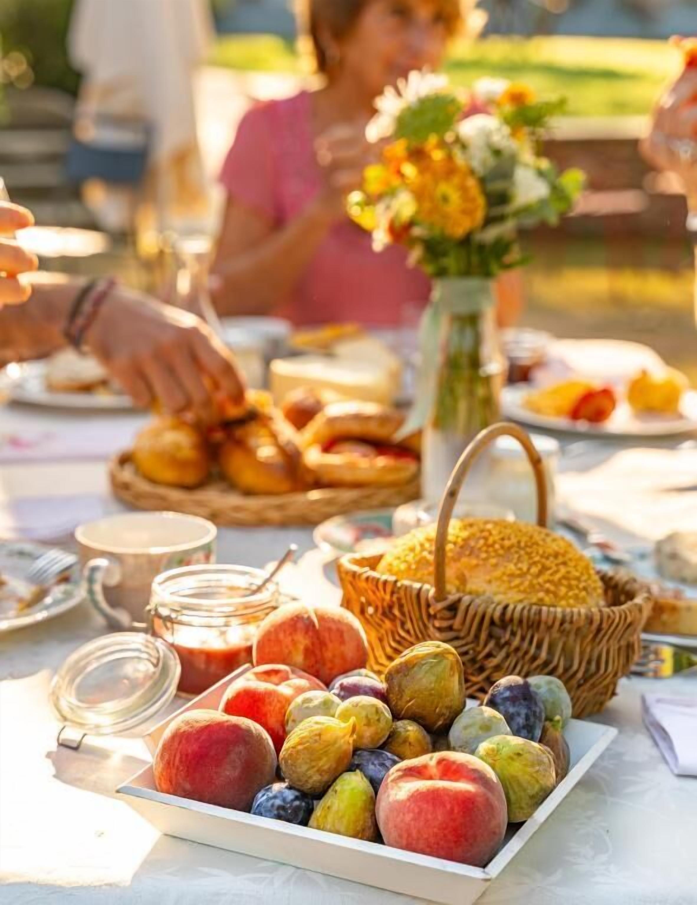 Un montaje para picnic con frutas variadas, pastelería y una cesta de pan.