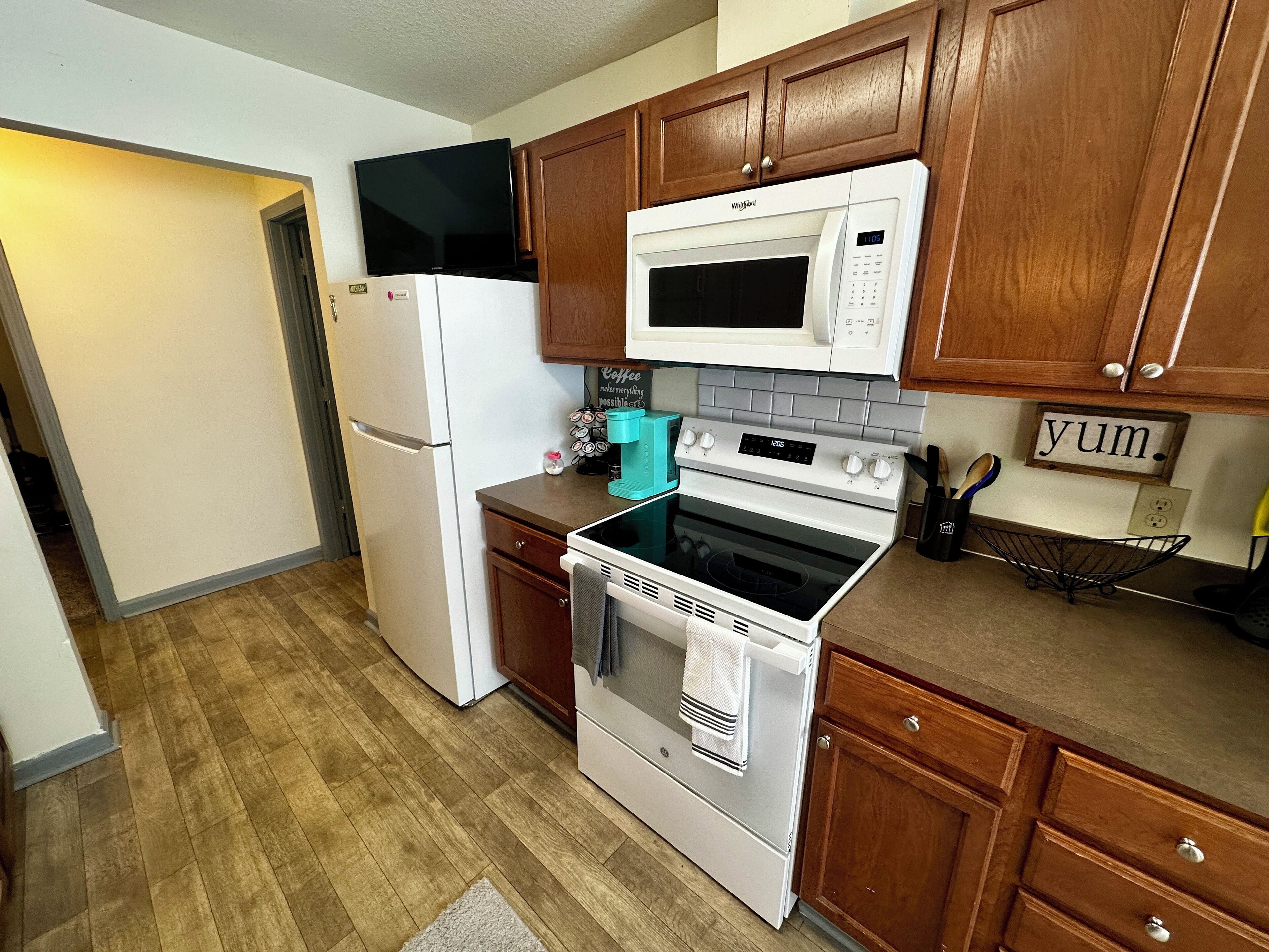 A kitchen with wooden cabinets, a white refrigerator, a microwave, an oven, and a coffee maker.