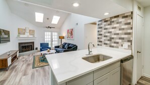 Een ruime woonkamer met een open haard, een eethoek en een keuken met een groot eiland.