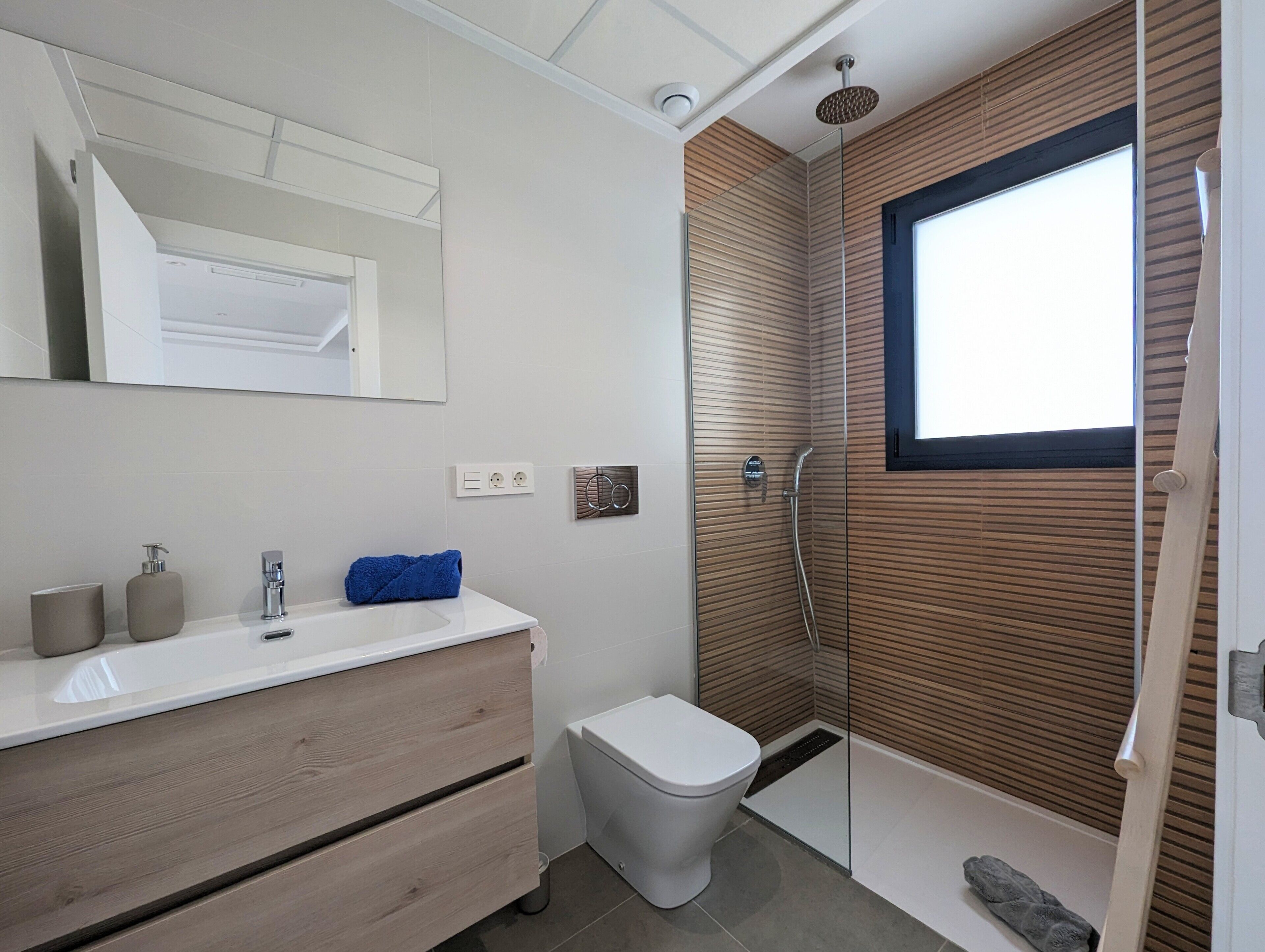 A modern bathroom with a shower, toilet, and vanity.