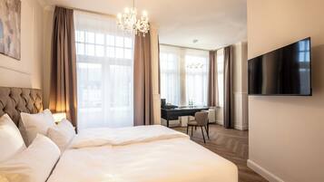 A hotel room with a large bed, a desk, a chair, and a TV on the wall.