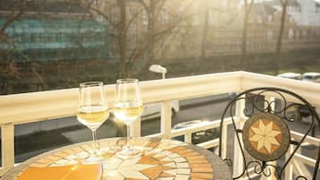 A round table with a mosaic top, two glasses of white wine, and a book on it.