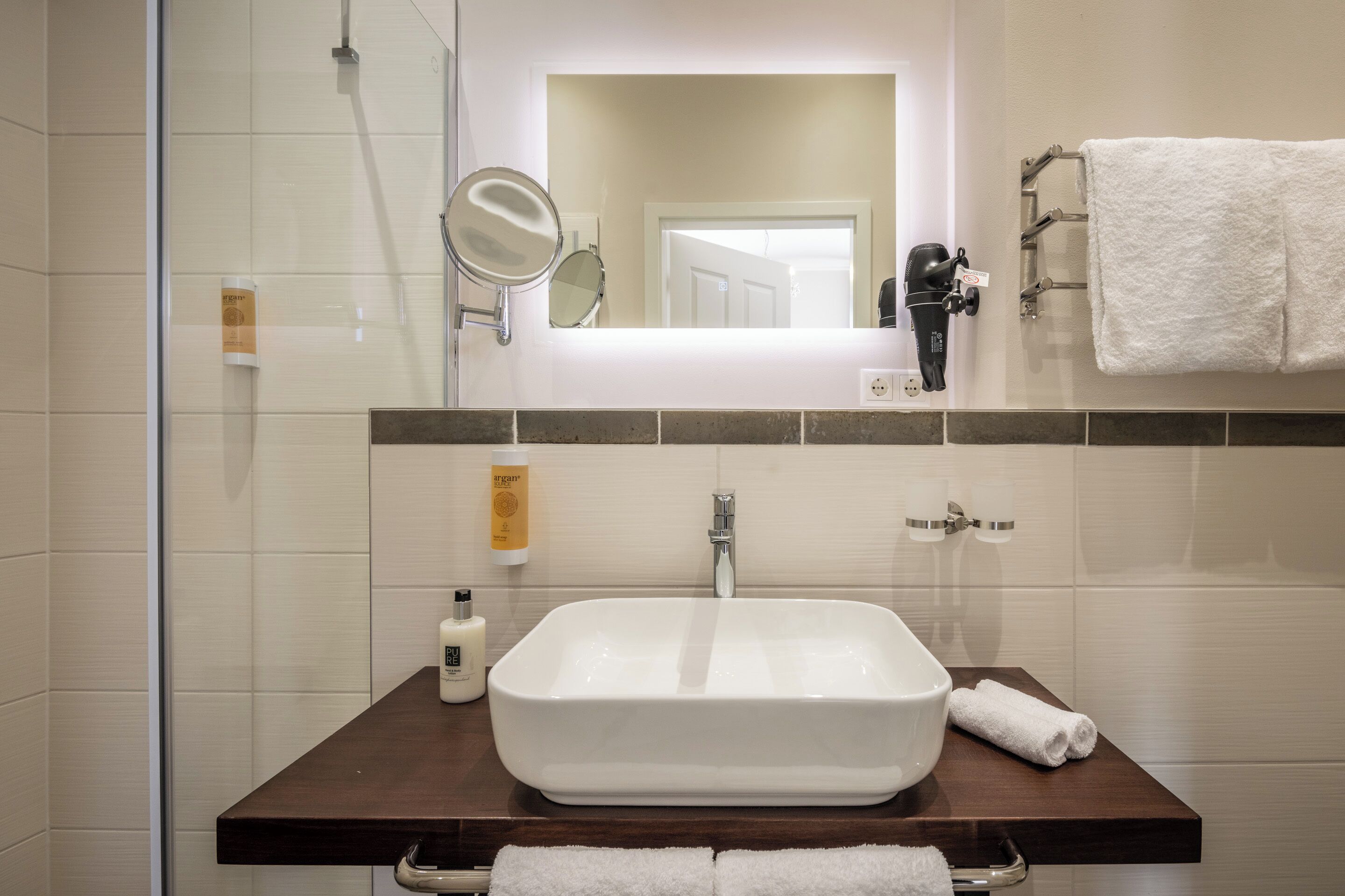 A bathroom with a white sink, a mirror, a hairdryer, and a towel rack.
