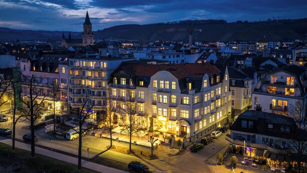 A multi-story hotel with a prominent entrance, a central courtyard, and a view of the surrounding urban area.