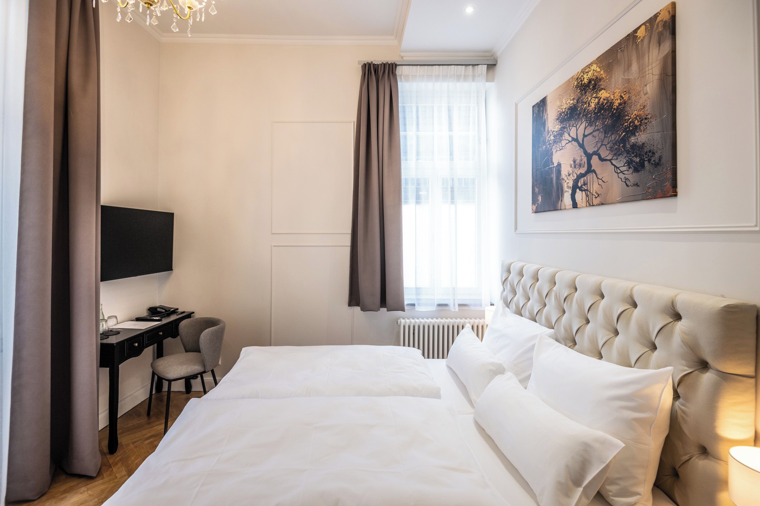 Ein Hotelzimmer mit einem großen Bett, einem Schreibtisch, einem Sessel, einem Fernseher und einem Bild an der Wand.