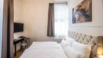 Ein Hotelzimmer mit einem großen Bett, einem Schreibtisch, einem Sessel, einem Fernseher und einem Bild an der Wand.