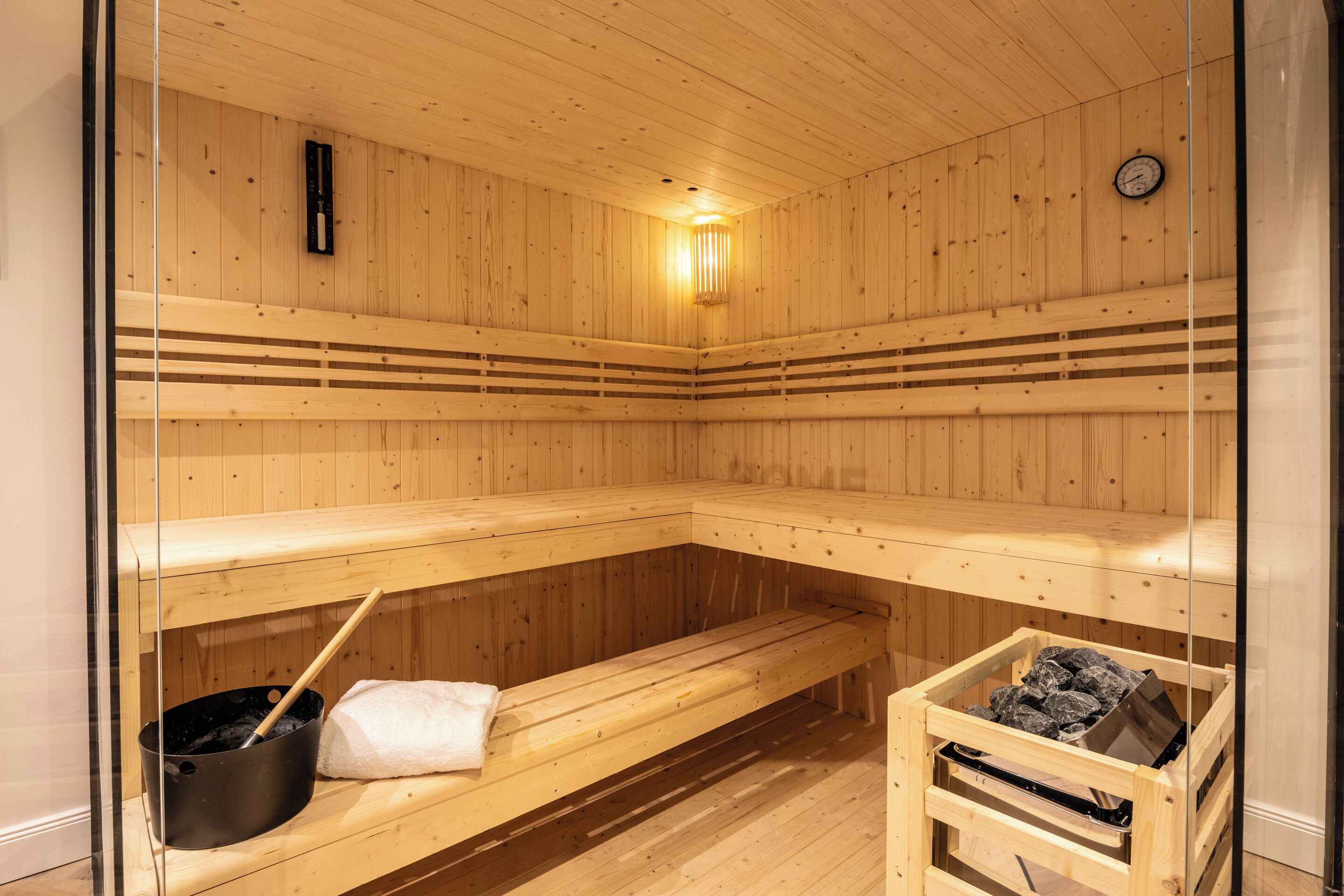 A sauna with wooden benches and a bench with a towel and a pot.