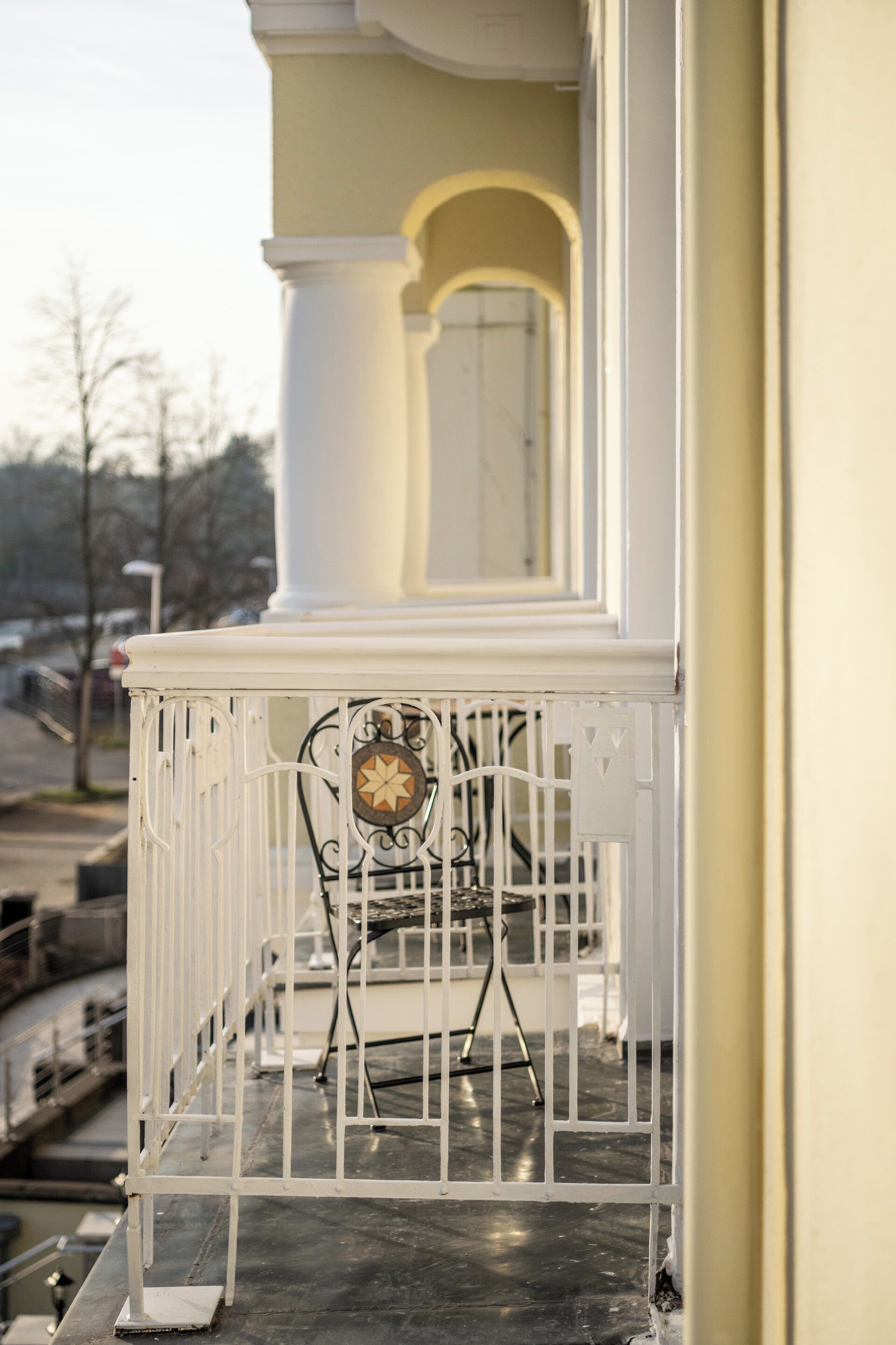 A balcony with a white railing, a small table, and a chair.