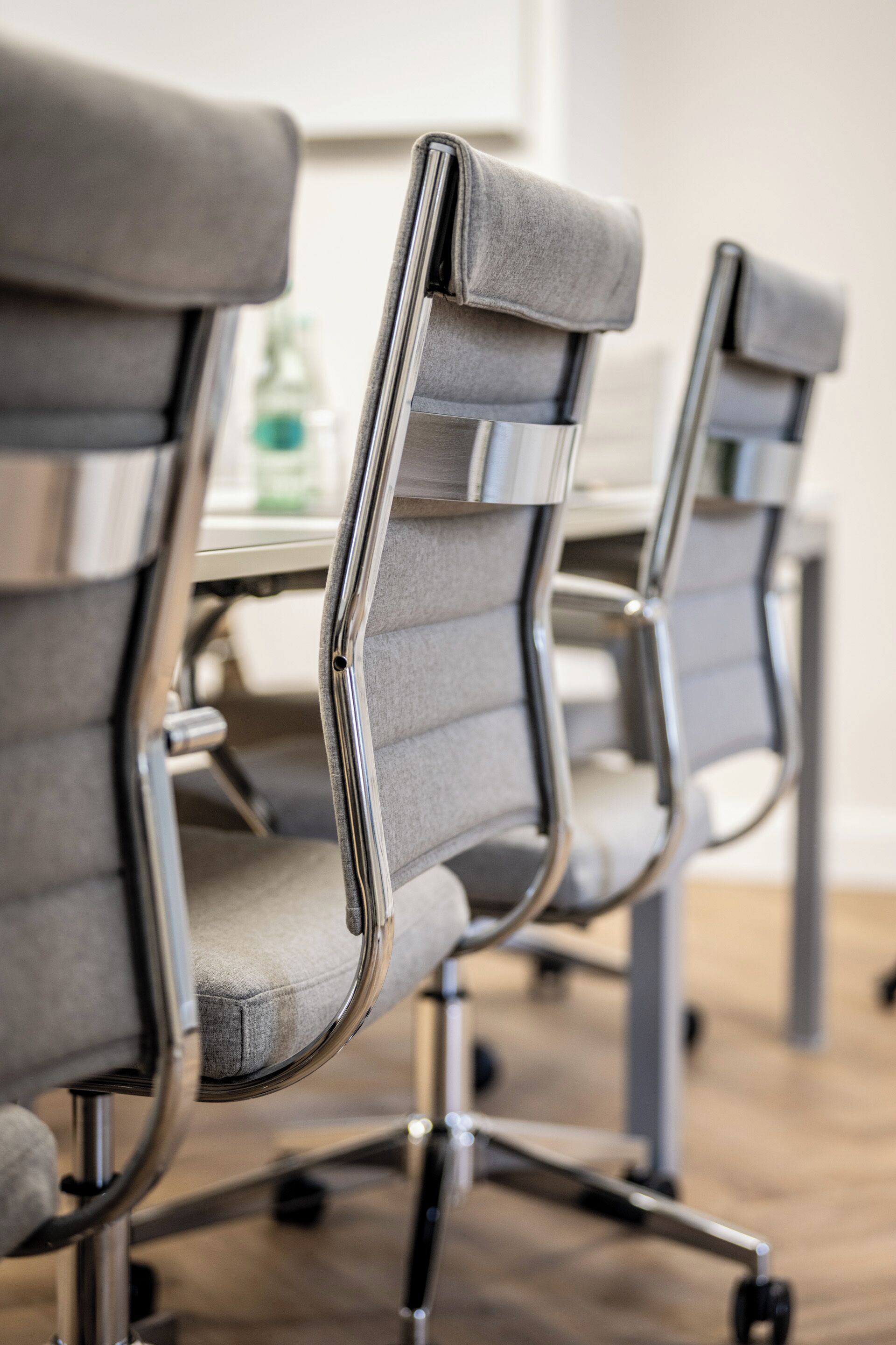 A row of office chairs with metal frames and grey upholstery.