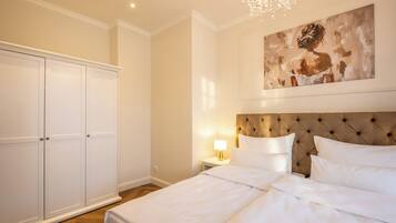 A bedroom with a large bed, a nightstand with a lamp, a wardrobe, and a painting on the wall.