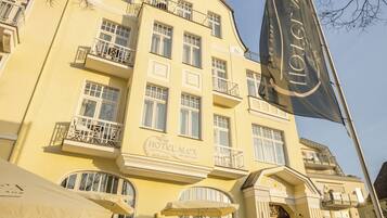 Un hotel con fachada amarilla, varios balcones y asientos al aire libre.