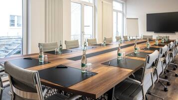 Un salón de conferencias con una mesa larga, varias sillas y una pantalla grande.