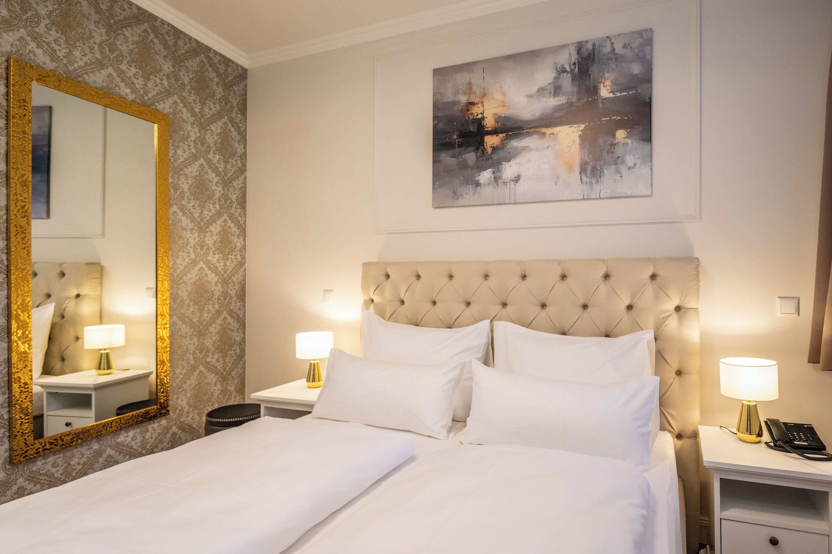 Un cuarto de hotel con una cama grande, dos mesitas de noche con lámparas, un espejo y un cuadro en la pared.
