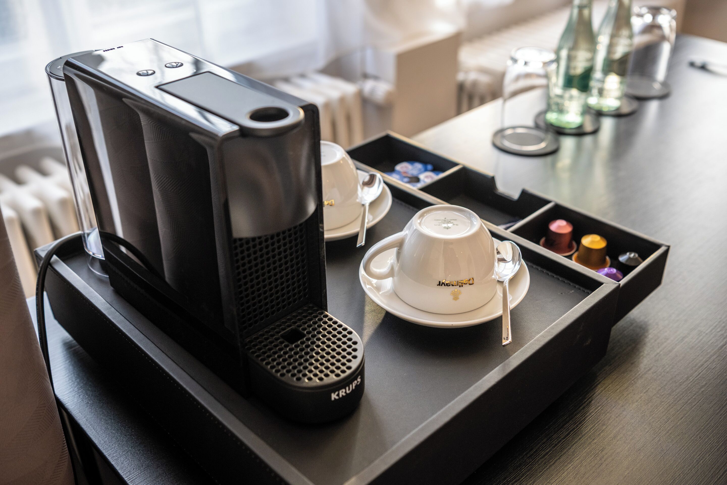 Eine Kaffeemaschine auf einem Tablett mit Tasse, Untertasse und Beilagen.