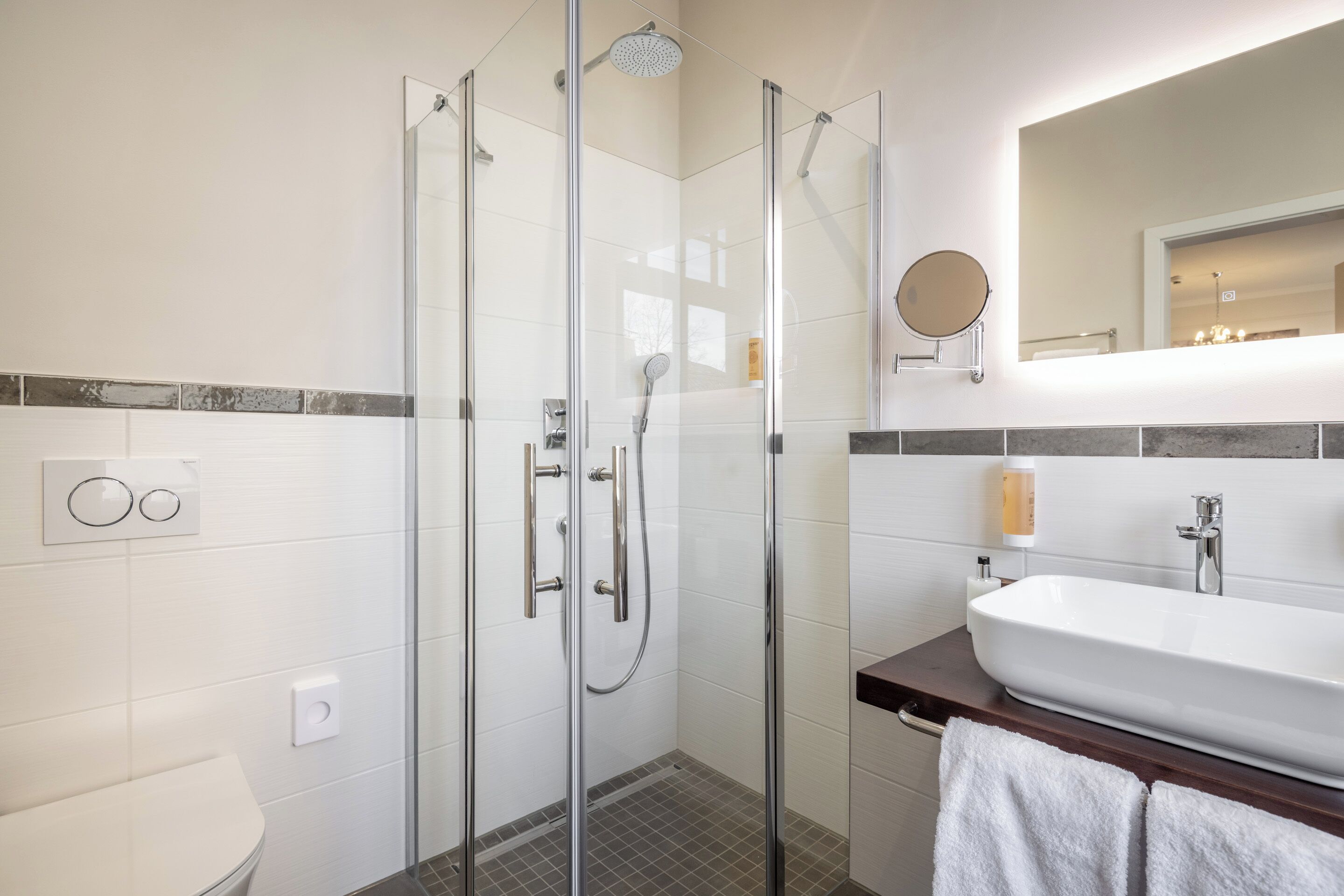 A modern bathroom with a glass-enclosed shower, a white sink, and a mirror above the sink.