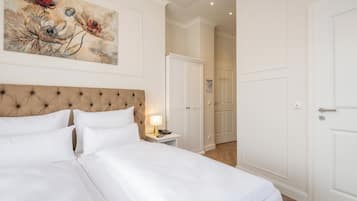 A hotel room with a large bed, a tufted headboard, a bedside table with a lamp, and a painting on the wall.
