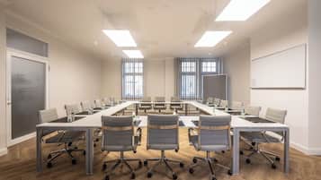 A conference room with a long table, multiple chairs, and a whiteboard.