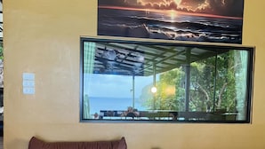 A room with a large window offering a view of the sea and a sunset. A brown leather sofa is positioned in front of the window. - The View Hostel (Ko Phi Phi)