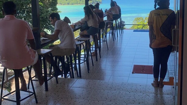 A covered outdoor seating area with a view of the ocean and mountains. - The View Hostel (Ko Phi Phi)