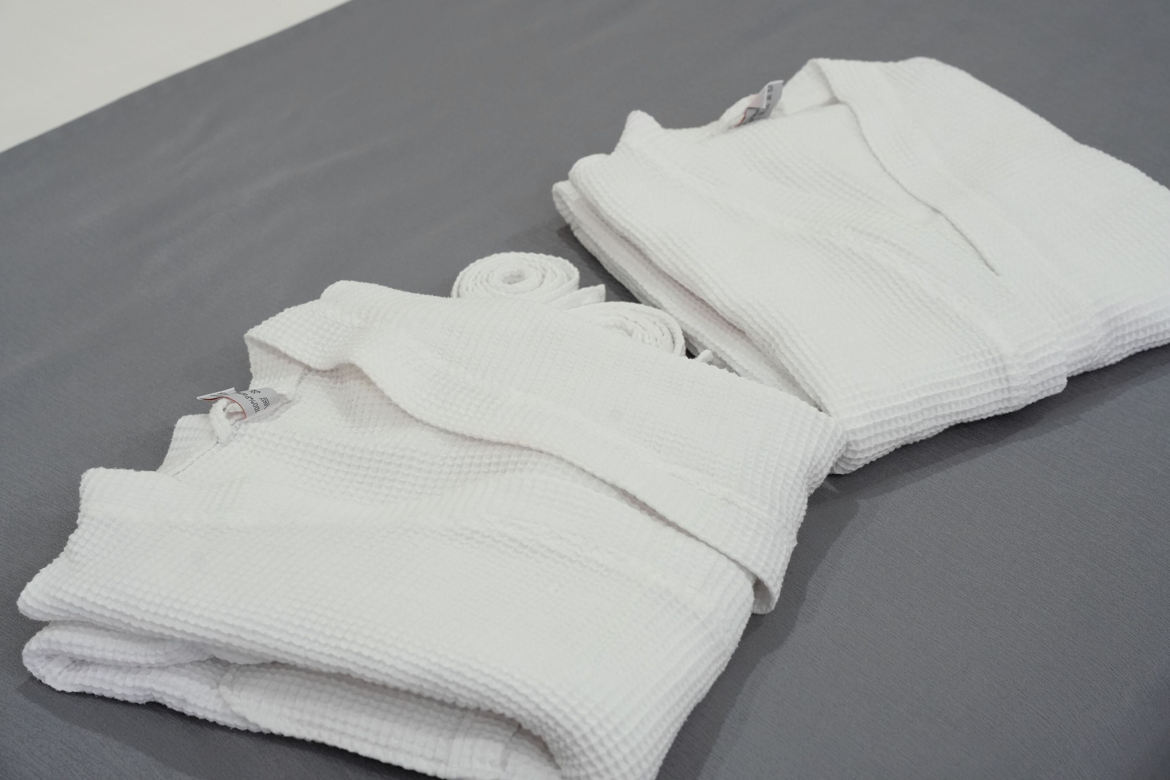 A neatly folded white towel on a grey surface.