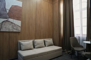 Una stanza con un divano color beige, una poltrona, un tavolino e un quadro appeso al muro.
