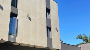 A modern building with a flat facade, large windows, and a clear sky. - AIRIS RESIDENCE hotel (Almaty)