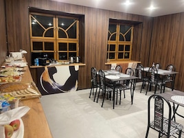 A restaurant with wooden panel walls, a buffet area with various food items, and multiple tables and chairs.