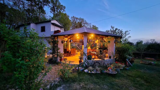 A house with a covered porch, a garden, and a bicycle. - Two Spacious Rooms w/ Balcony in Naturalist's Home (Teda)