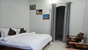 A bedroom with a bed, a wooden chair, a small table, and a door leading to another room. - Two Spacious Rooms w/ Balcony in Naturalist's Home (Teda)