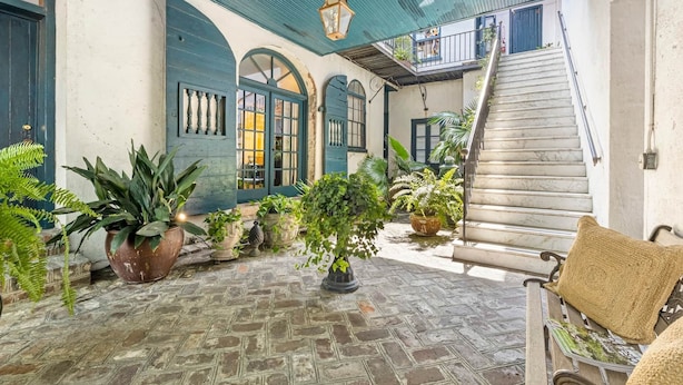 A courtyard with a stone floor, potted plants, a wooden bench, and a staircase leading to an upper level. - The Master Suite - A spacious suite inspired by Charleston’s grace and charm (Charleston)