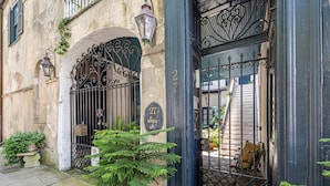 A building with a wrought iron gate, a potted plant, and a sign indicating the address. - The Master Suite - A spacious suite inspired by Charleston’s grace and charm (Charleston)