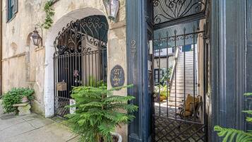 A building with a wrought iron gate, a potted plant, and a sign indicating the address.