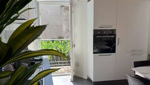 A modern kitchen with white cabinets, a built-in oven, and a dining area with a table and chairs. - "La Dama alla Finestra," charming apartment in the historic center of Como. (Como)