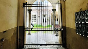 A corridor with a gate leading to a courtyard, stone flooring, and a hanging light fixture. - "La Dama alla Finestra," charming apartment in the historic center of Como. (Como)
