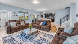A spacious living room with two brown leather sofas, a coffee table, and a large blue and white rug. - Ohana Memories At Championsgate (Davenport)