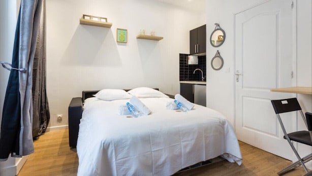 A hotel room with a bed, a desk, a chair, a sink, and a door. - Cosy Studio, 1 chambre, Père Lachaise, Place de la nation (Paris)