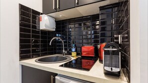 A modern kitchen with black tiled backsplash, stainless steel appliances, and a white countertop. - Cosy Studio, 1 chambre, Père Lachaise, Place de la nation (Paris)