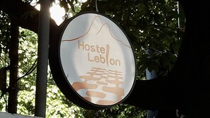 Un panneau circulaire portant l’inscription « Hostel Leblon » et représentant la silhouette d’une montagne.